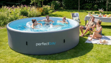 Pool Gartenparty - ein Paar sitzt am Gartenpool und drei Personen baden im Wasser am sonnigen Tag