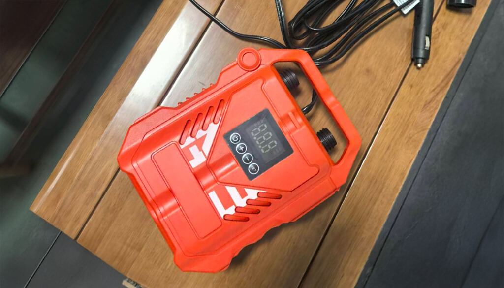 Eine rote Poolpumpe mit Kabel liegt auf einem Tischblatt aus Holz